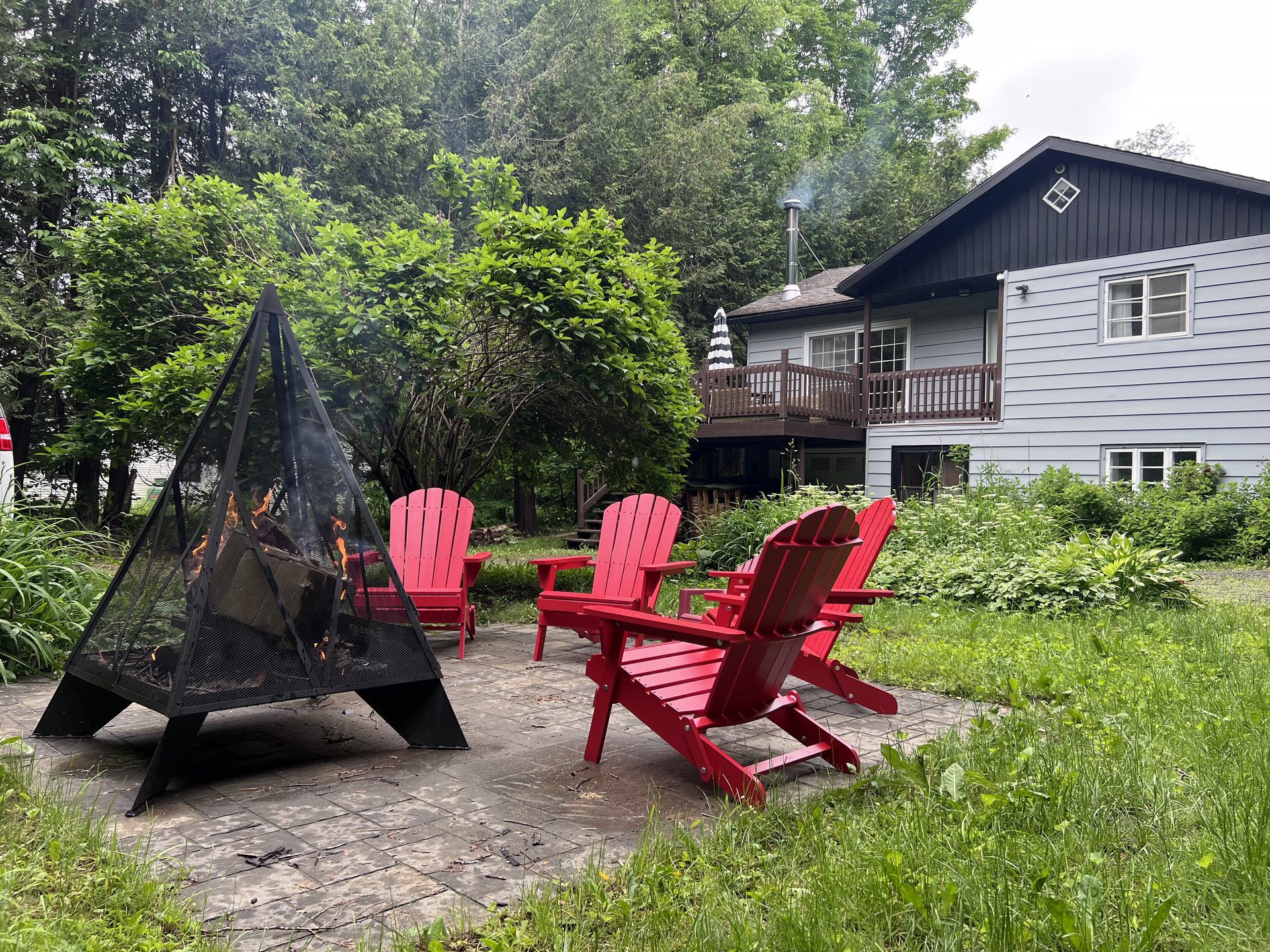 Outdoor patio with red Adirondack chairs and fire bowl